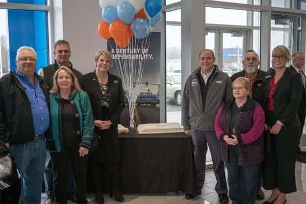 Members of the Wheeler family and team gathered with balloons and a cake inside a Wheelers dealership