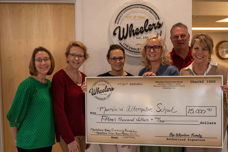 Wheelers and school representatives holding a check for Marshfield Alternative School