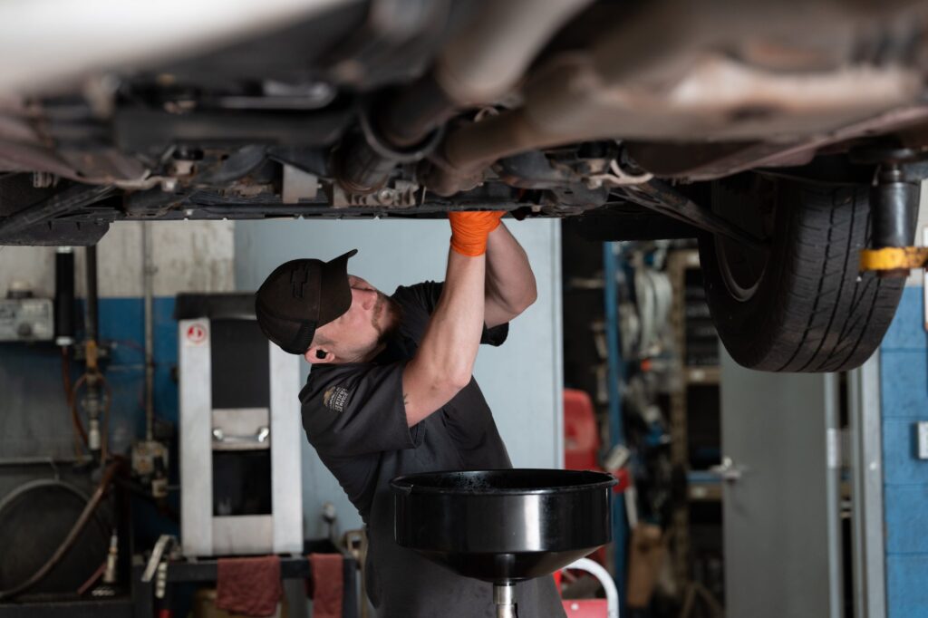 A Wheelers service technician working under a vehicle on a lift